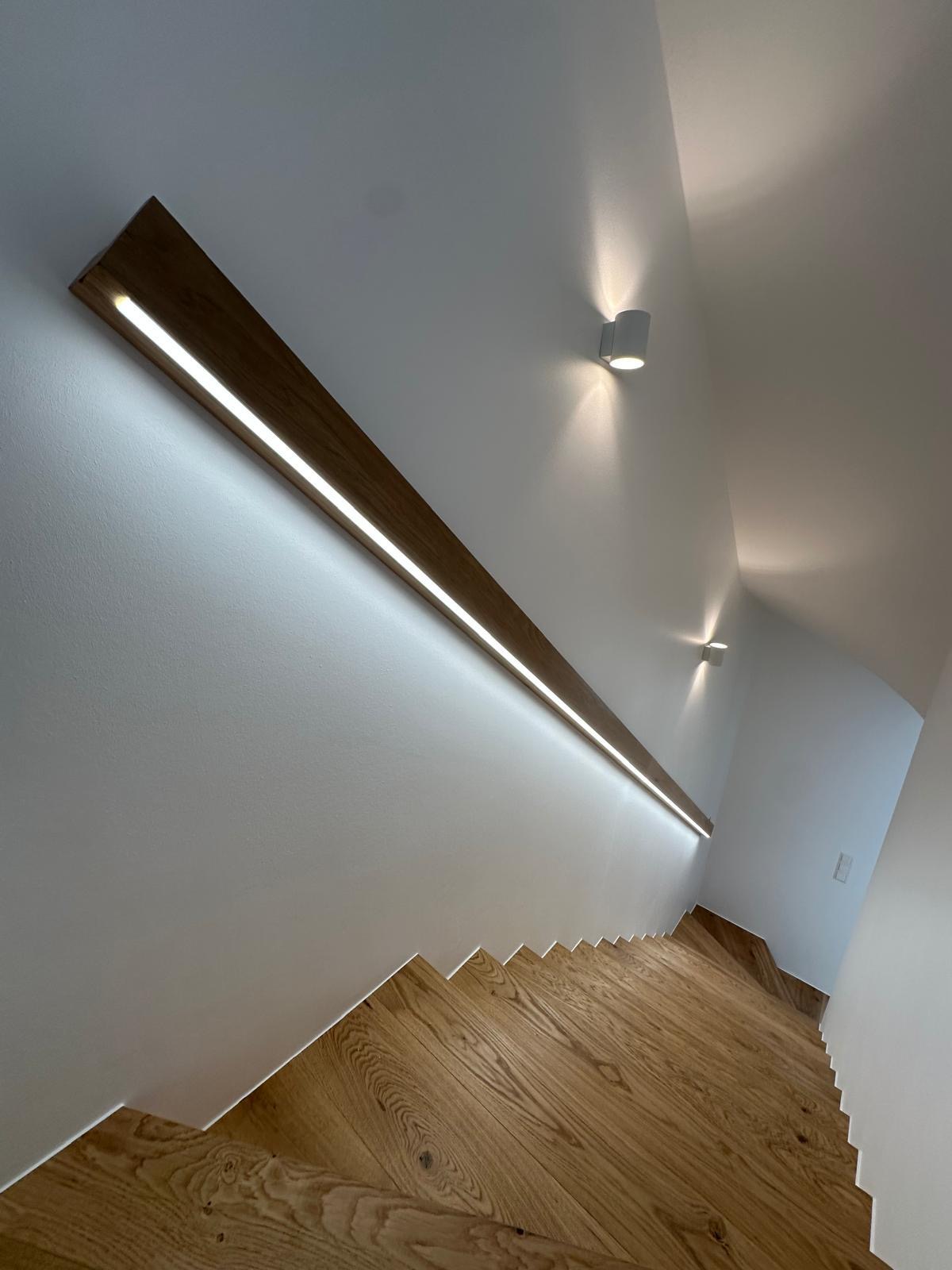 Main courante en bois avec ruban LED intégré dans cage d'escalier